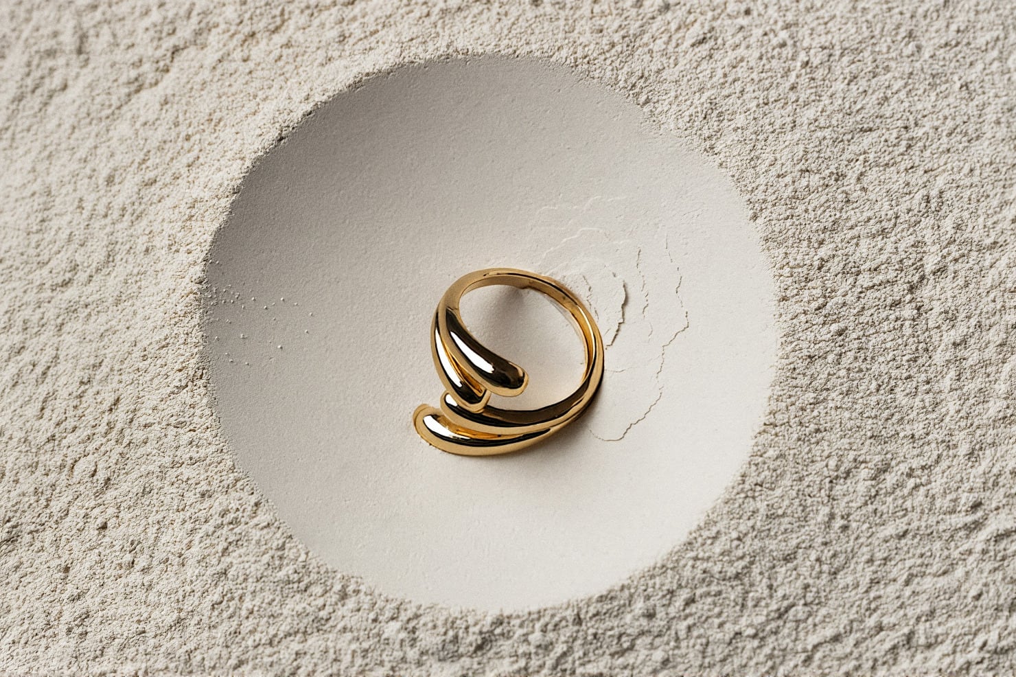 A gold ring resting in ivory sand